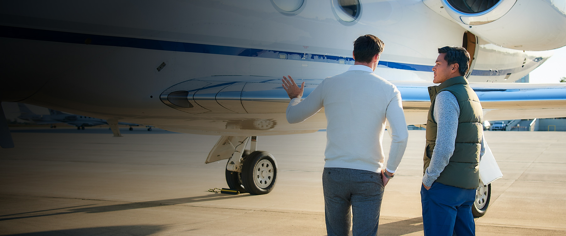 two men talking in front of private jet