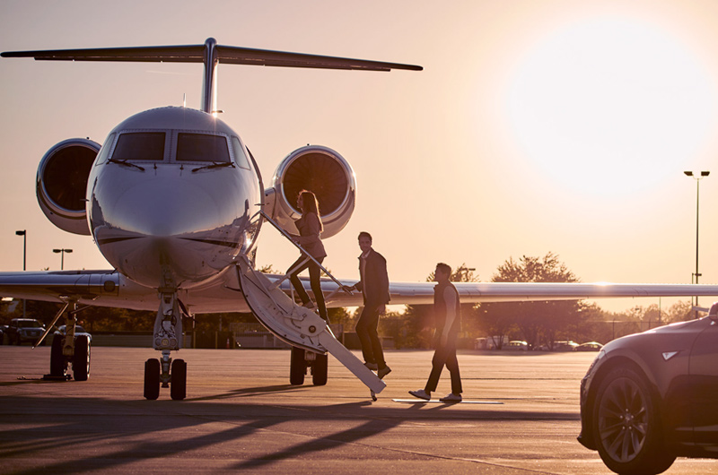 men boarding private jet with sunset behind