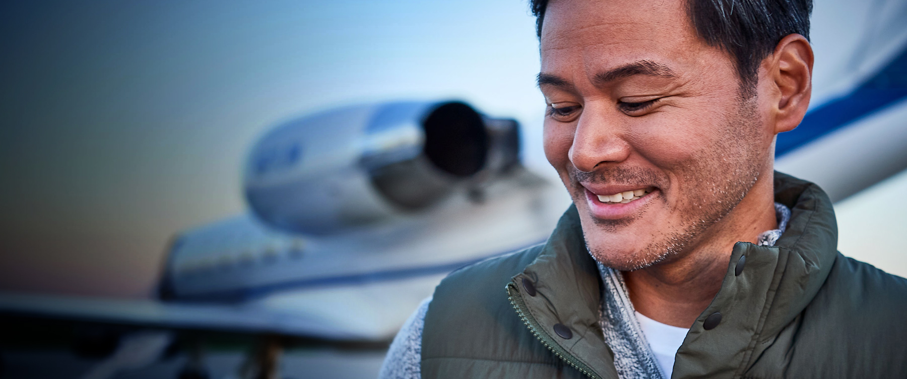 man smiling in front of private jet blurred in background