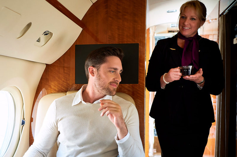 flight attendant serving drink on private jet